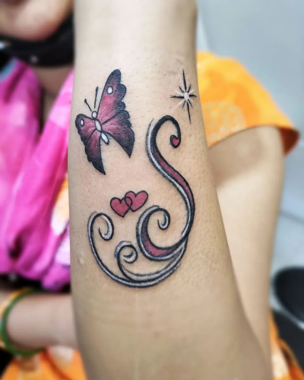 S letter tattoo with peacock feather done at xpose tattoos jaipur